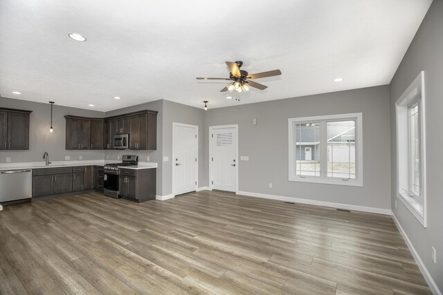 kitchen with a sink, dark brown cabinets, baseboards, light countertops, and appliances with stainless steel finishes