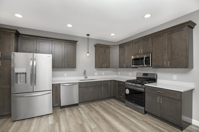 kitchen with recessed lighting, stainless steel appliances, dark brown cabinets, a sink, and light wood-style flooring