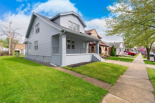view of side of property featuring brick siding, a shingled roof, a yard, and covered porch