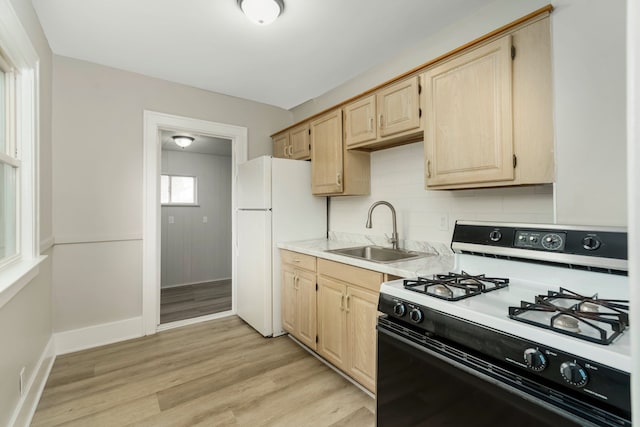 kitchen featuring gas range oven, a sink, light brown cabinetry, and light countertops