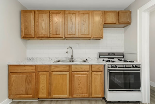 kitchen featuring a sink, light countertops, white gas stove, and backsplash