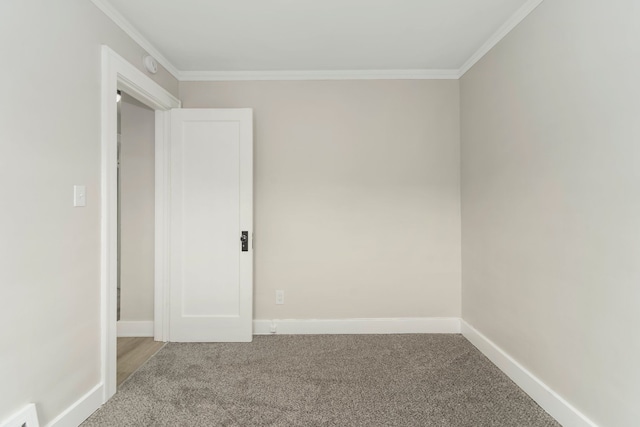spare room with carpet floors, crown molding, visible vents, and baseboards