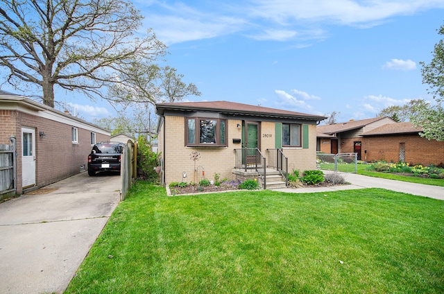 view of front of property featuring fence, driveway, brick siding, and a front yard