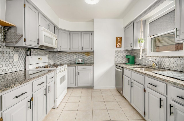 kitchen featuring decorative backsplash, light stone countertops, a sink, light tile patterned floors, and white appliances