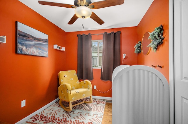 sitting room featuring baseboards, ceiling fan, and wood finished floors