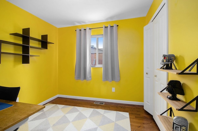 office space with baseboards, wood finished floors, and visible vents