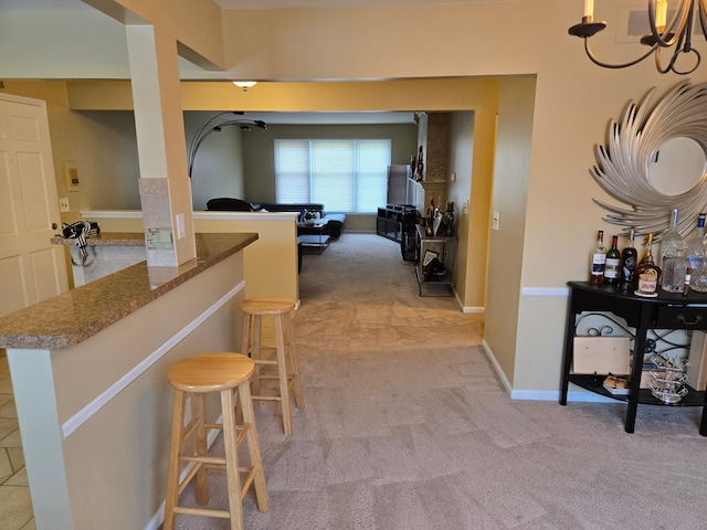 corridor featuring a chandelier, light carpet, and baseboards
