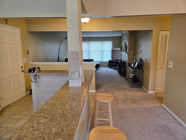 hall featuring light carpet, light tile patterned flooring, and baseboards