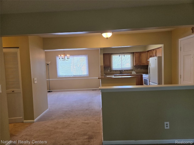 450 Billingsgate Unit C, Bloomfield Hills, MI 48301 - kitchen featuring white appliances, light carpet, a chandelier, brown cabinetry, and a peninsula
