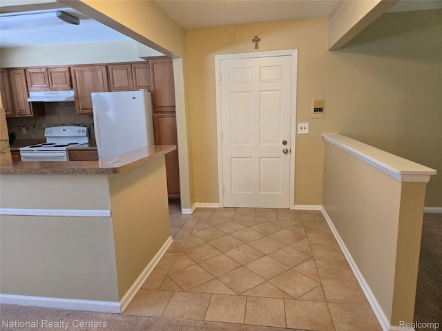 450 Billingsgate Unit C, Bloomfield Hills, MI 48301 - kitchen with white appliances, under cabinet range hood, brown cabinetry, a peninsula, and light tile patterned flooring