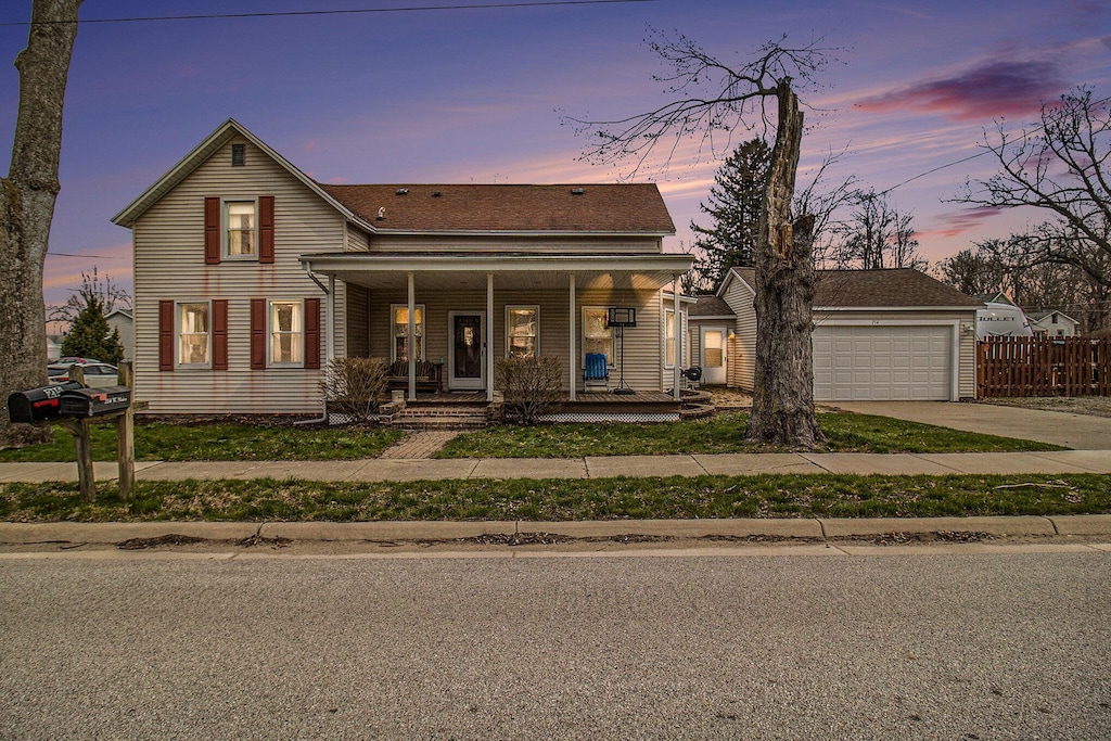 view of front of home with concrete driveway, an attached garage, fence, a porch, and roof with shingles