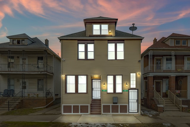 back of house featuring a balcony and entry steps