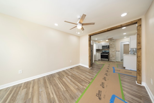 unfurnished living room with ceiling fan, baseboards, recessed lighting, and light wood-style floors