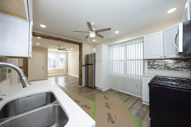 kitchen with stainless steel appliances, a ceiling fan, wood finished floors, and a sink