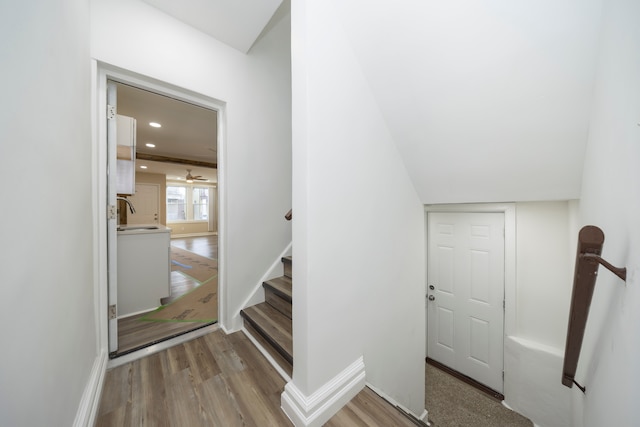 stairway with wood finished floors, recessed lighting, a ceiling fan, and baseboards