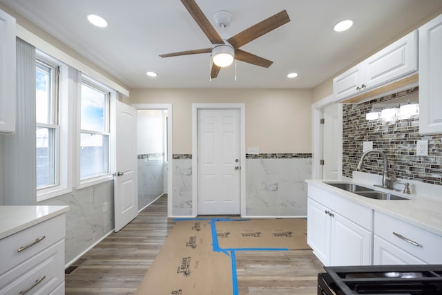 kitchen with tile walls, a sink, ceiling fan, light countertops, and white cabinets