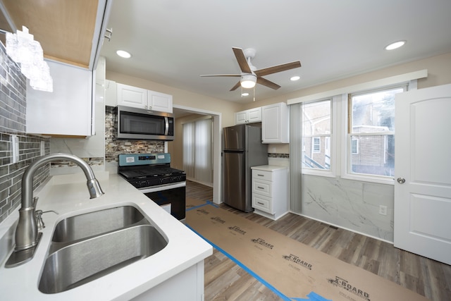 kitchen with appliances with stainless steel finishes, ceiling fan, light countertops, and a sink