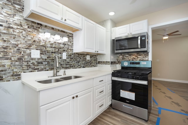 kitchen featuring tasteful backsplash, white cabinets, a sink, appliances with stainless steel finishes, and light wood-style floors