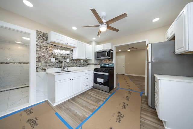 kitchen featuring appliances with stainless steel finishes, white cabinetry, a ceiling fan, and a sink
