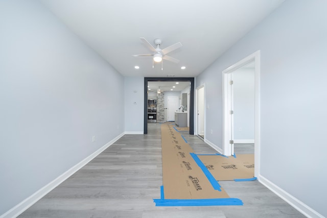 corridor with wood finished floors, recessed lighting, and baseboards