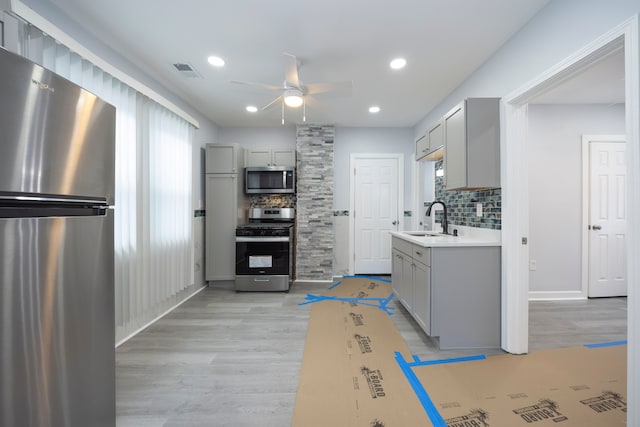 kitchen with gray cabinetry, a wealth of natural light, appliances with stainless steel finishes, and a sink