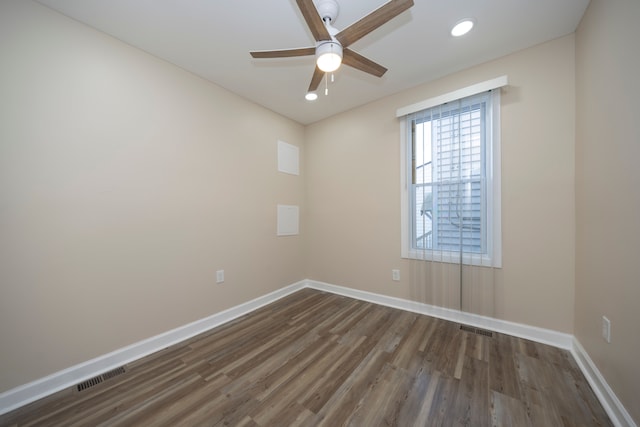 spare room featuring visible vents, ceiling fan, dark wood-style flooring, and baseboards