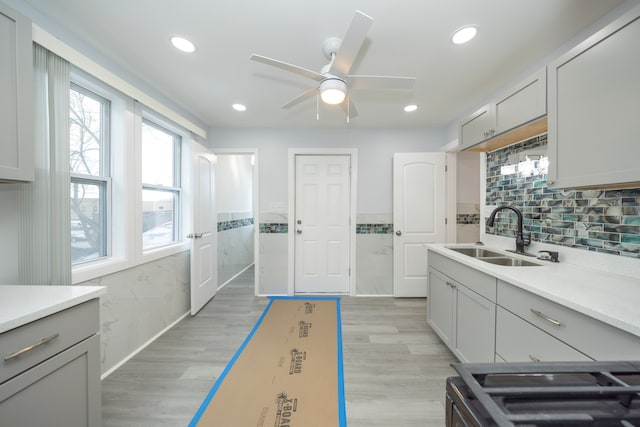 kitchen with tile walls, a sink, ceiling fan, and light countertops