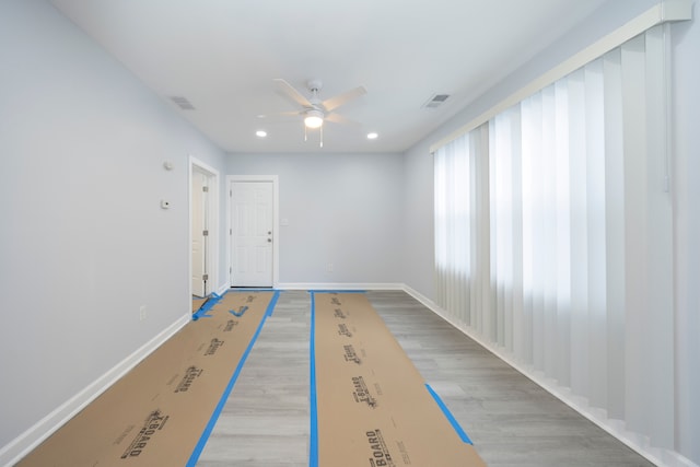 interior space with visible vents, light wood-type flooring, a ceiling fan, and baseboards