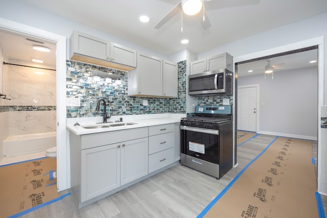 kitchen featuring stainless steel appliances, ceiling fan, light countertops, and a sink