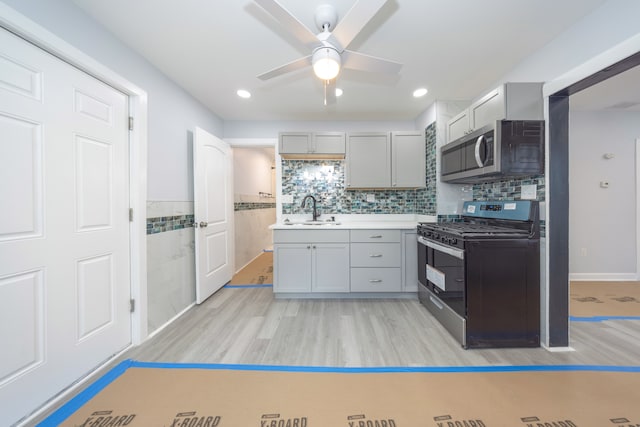 kitchen with light wood-type flooring, stainless steel appliances, a ceiling fan, and a sink
