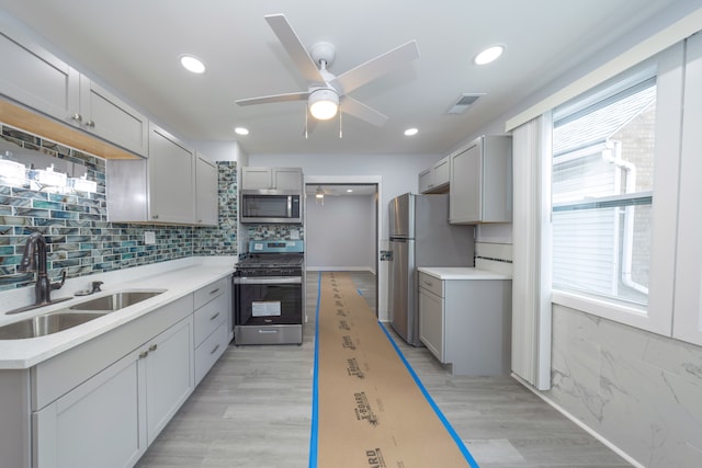 kitchen with a sink, stainless steel appliances, gray cabinets, a ceiling fan, and visible vents