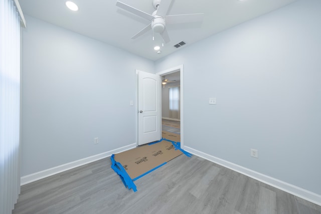 unfurnished room with a ceiling fan, visible vents, wood finished floors, and baseboards