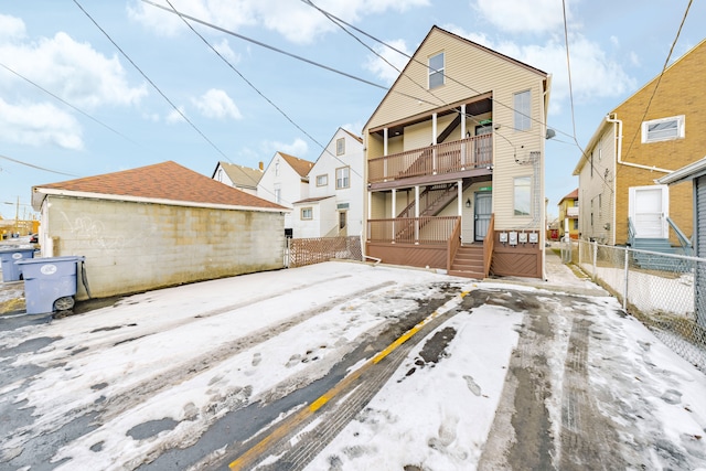 snow covered rear of property with fence and a balcony