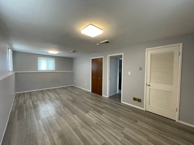 interior space with baseboards, wood finished floors, and visible vents