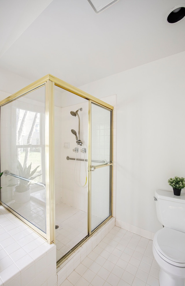 bathroom featuring toilet, a shower stall, and tile patterned flooring
