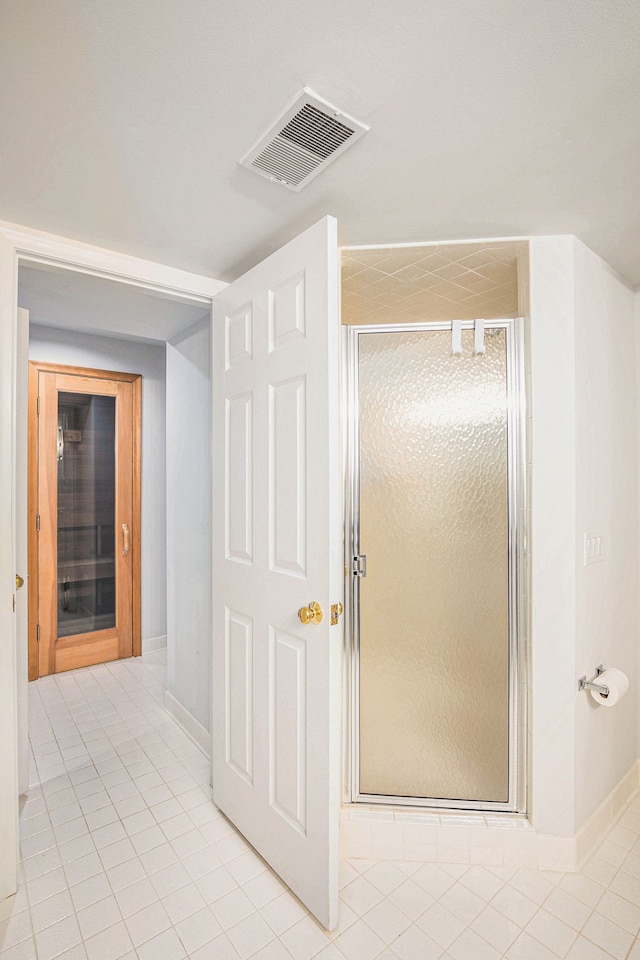 full bathroom featuring tile patterned flooring, visible vents, a shower stall, and baseboards
