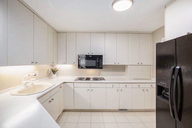kitchen with light tile patterned floors, a sink, visible vents, light countertops, and black appliances