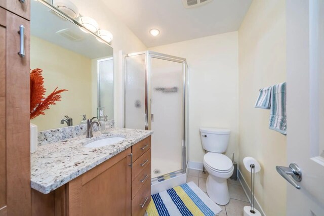 bathroom with a shower stall, tile patterned floors, vanity, baseboards, and toilet