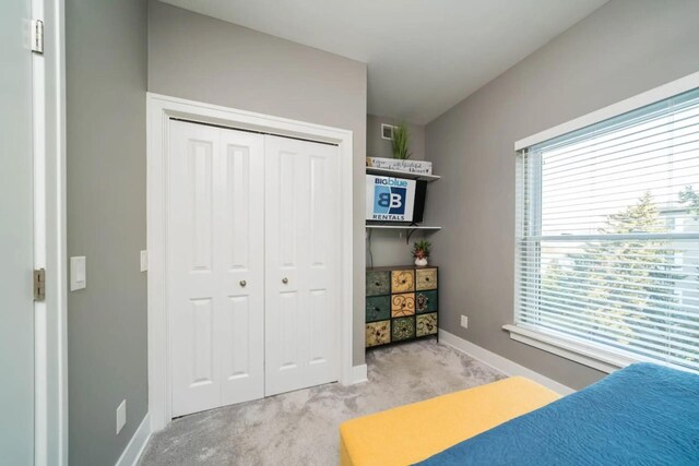bedroom featuring baseboards, a closet, and light colored carpet