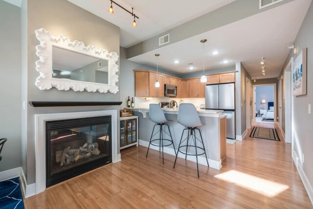 kitchen with a kitchen breakfast bar, stainless steel appliances, light countertops, a peninsula, and visible vents