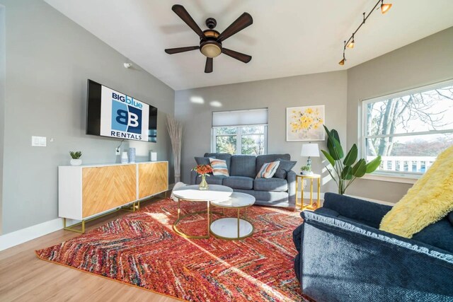 living area with baseboards, wood finished floors, and ceiling fan
