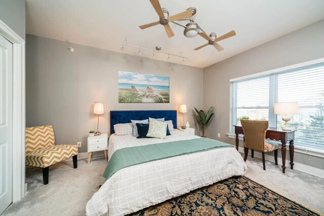 bedroom with track lighting, ceiling fan, carpet floors, and baseboards