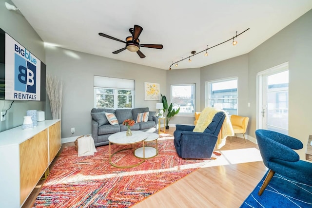living area with rail lighting, baseboards, wood finished floors, and ceiling fan