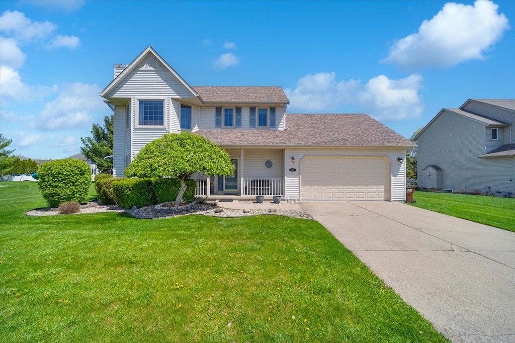 traditional-style house with a garage, a chimney, concrete driveway, and a front lawn
