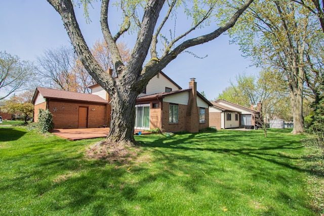 back of property featuring brick siding, a lawn, and a wooden deck