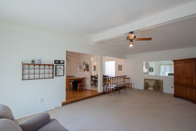 living area with vaulted ceiling with beams, a fireplace, ceiling fan, and light colored carpet