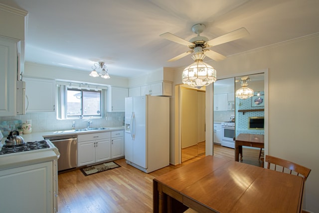 kitchen featuring decorative backsplash, a sink, light countertops, light wood finished floors, and white appliances