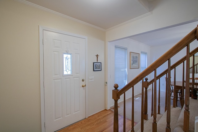 entryway featuring light wood-style floors, ornamental molding, and stairs