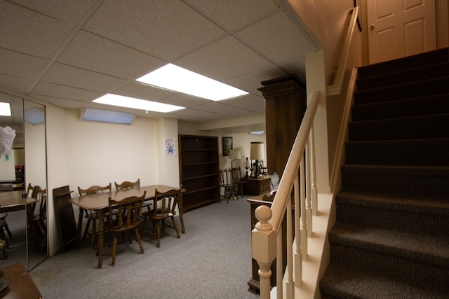 dining area with carpet, stairs, and a paneled ceiling