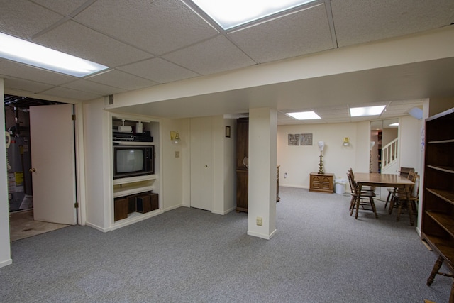 finished below grade area with carpet floors, baseboards, water heater, a drop ceiling, and stairs